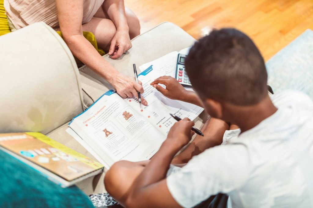 Ein Kind erhält Nachhilfe bei den Hausaufgaben, wodurch Bildung und Lernen hervorgehoben werden.